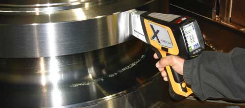 Olympus Innov-X DELTA Premium XRF alloy analyzer testing a stainless steel fixture for quality control
